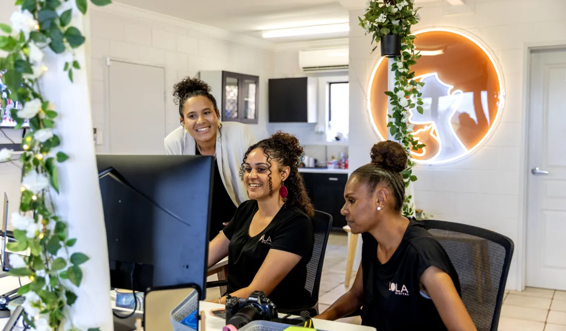 3 girls work in an office looking at the same screen