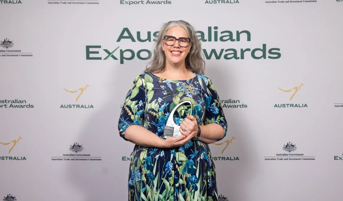 A lady holds an award smiling