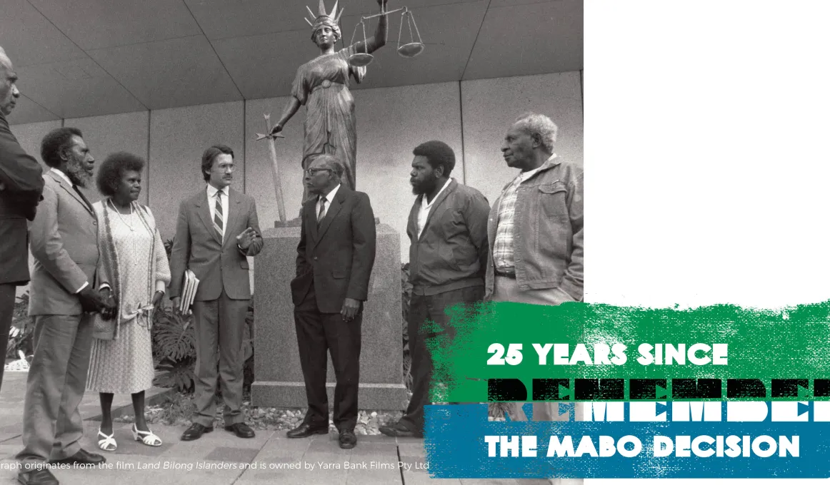 Five Indigenous men, one Indigenous woman and one non-Indigenous man stand in half circle in front of a statue of a woman holding a sword in the right hand and a set of scales in the left. Words: 25 years since The Mabo Decision Remember