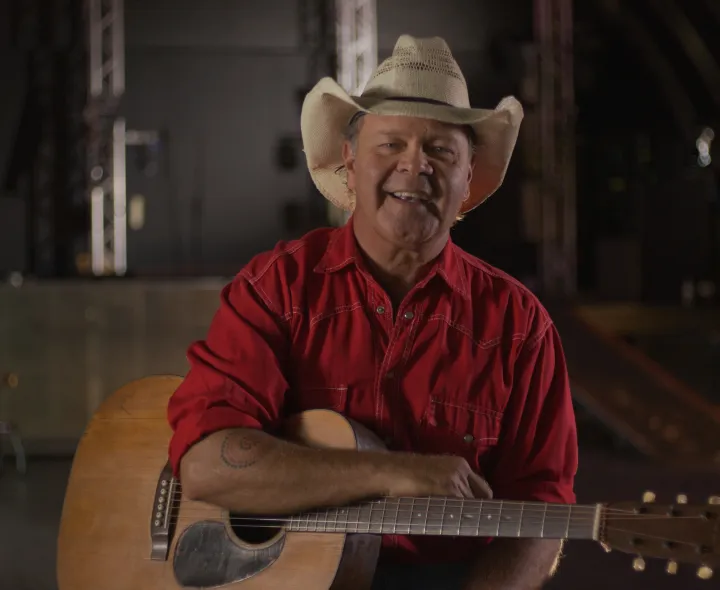 A man sitting holding a guitar