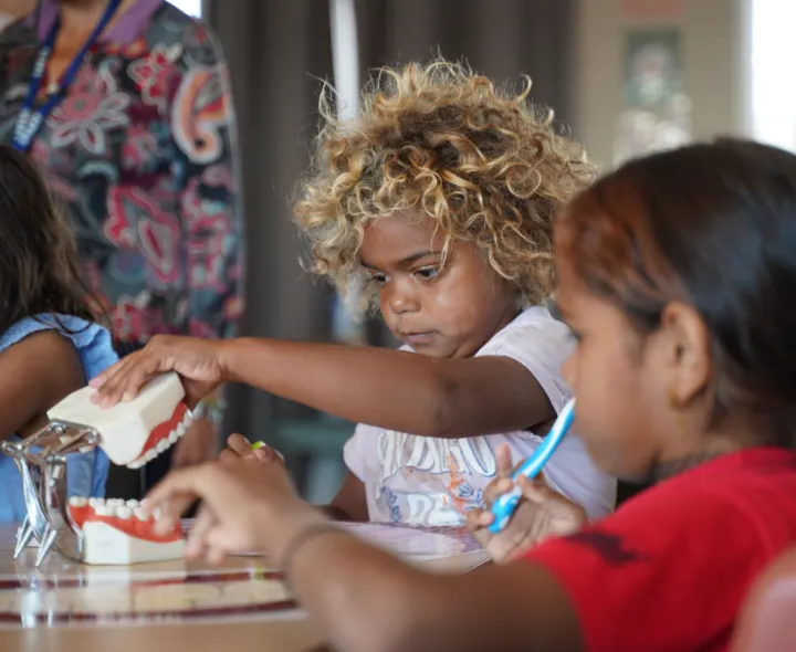Two children learn from a model jaw and teeth