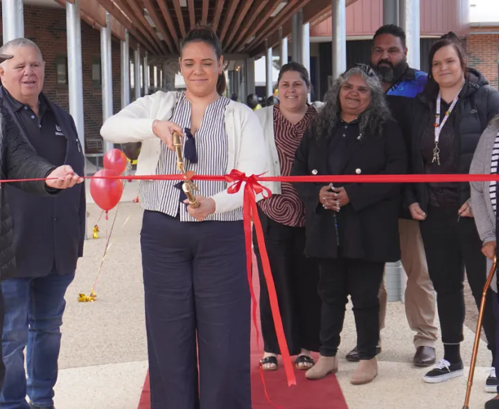 A lady cuts the ribbon to open a new building