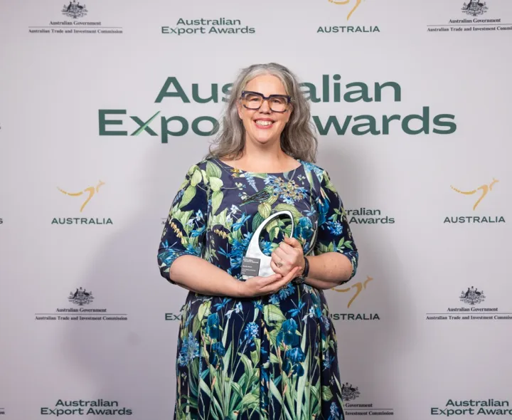 A lady holds an award smiling