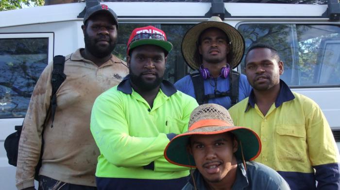 Five young Torres Strait Islander men standing in front of a mini-van smiling