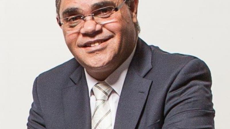 Aboriginal man in suit and wearing glasses.