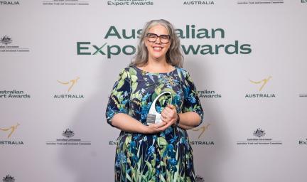 A lady holds an award smiling